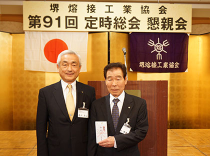 大阪府優良技能者表彰を受賞した梅田照義氏（右）に辻川正人理事長（左）から記念品が贈られた