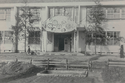 創立（昭和26年）時の湊西小学校。
玄関ホールは独特な雰囲気があった。写真は昭和30年代前半、体育祭開催時　前の畑に風車があった。